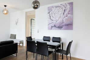 A modern dining area with a table and chairs, a sofa, and a wall-mounted flower painting. - VISIONAPARTMENTS Zurich Hardstrasse (Zürich)