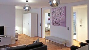 En moderne stue med sofa, spisebord og stole. Et stort kunstværk hænger på væggen, og en bænk står i hjørnet.