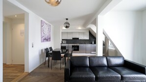 A modern living room with a black leather sofa, a dining area with a table and chairs, and a kitchen with contemporary appliances. - VISIONAPARTMENTS Zurich Hardstrasse (Zürich)