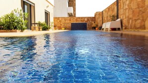 A swimming pool with clear blue water, surrounded by stone walls and modern buildings. - The Ocean Villa  (Dakhla)