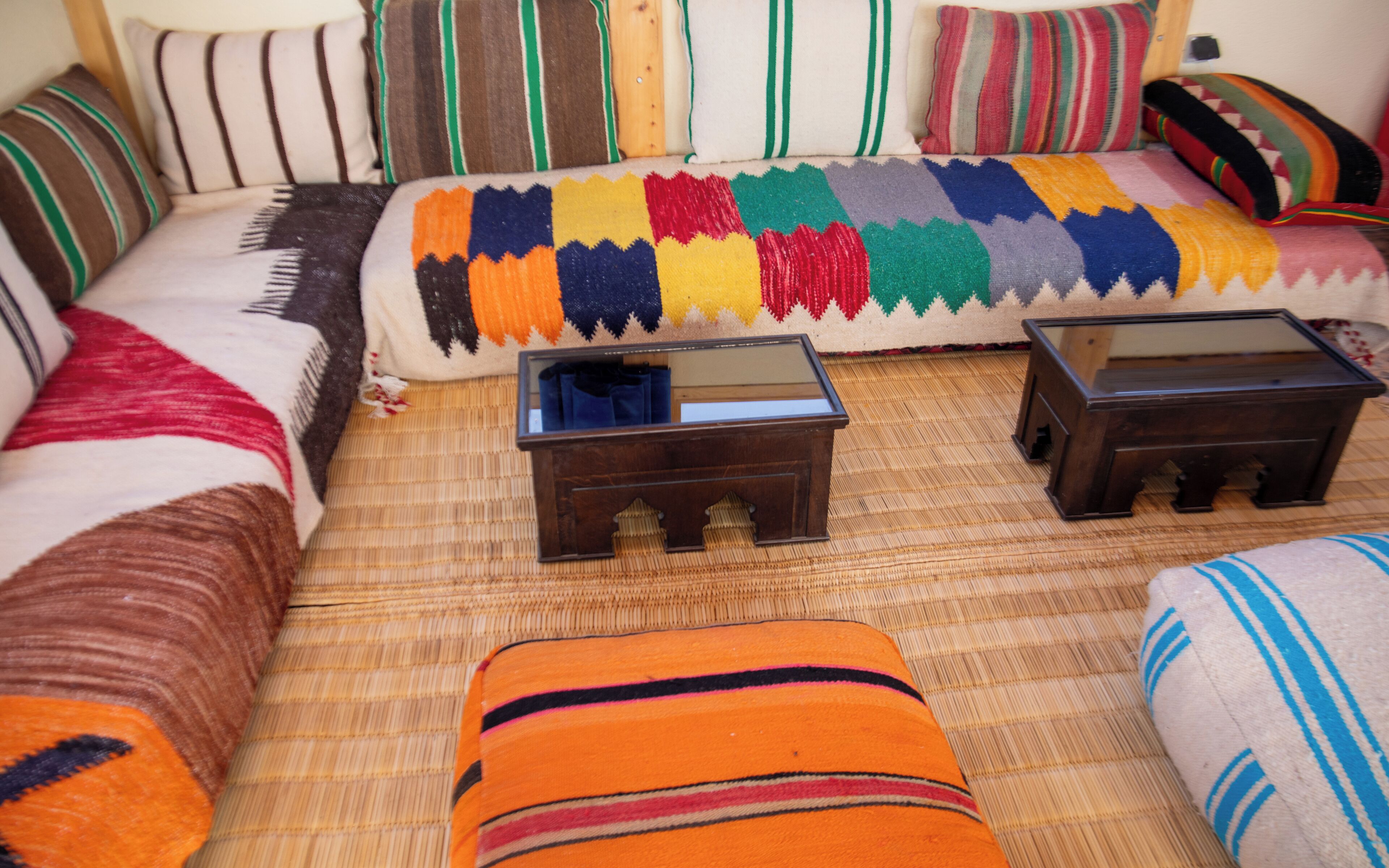 A bed with a colorful blanket, two wooden nightstands, and striped pillows.