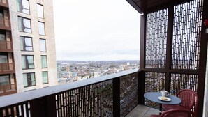 A balcony with a view of a cityscape, a table with chairs, and a decorative partition. - The Blossoms (Croydon)