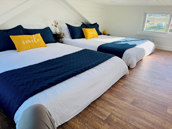 Un dormitorio con dos camas, cada una con ropa de cama azul oscuro y una almohada amarilla con la palabra 'smile'.