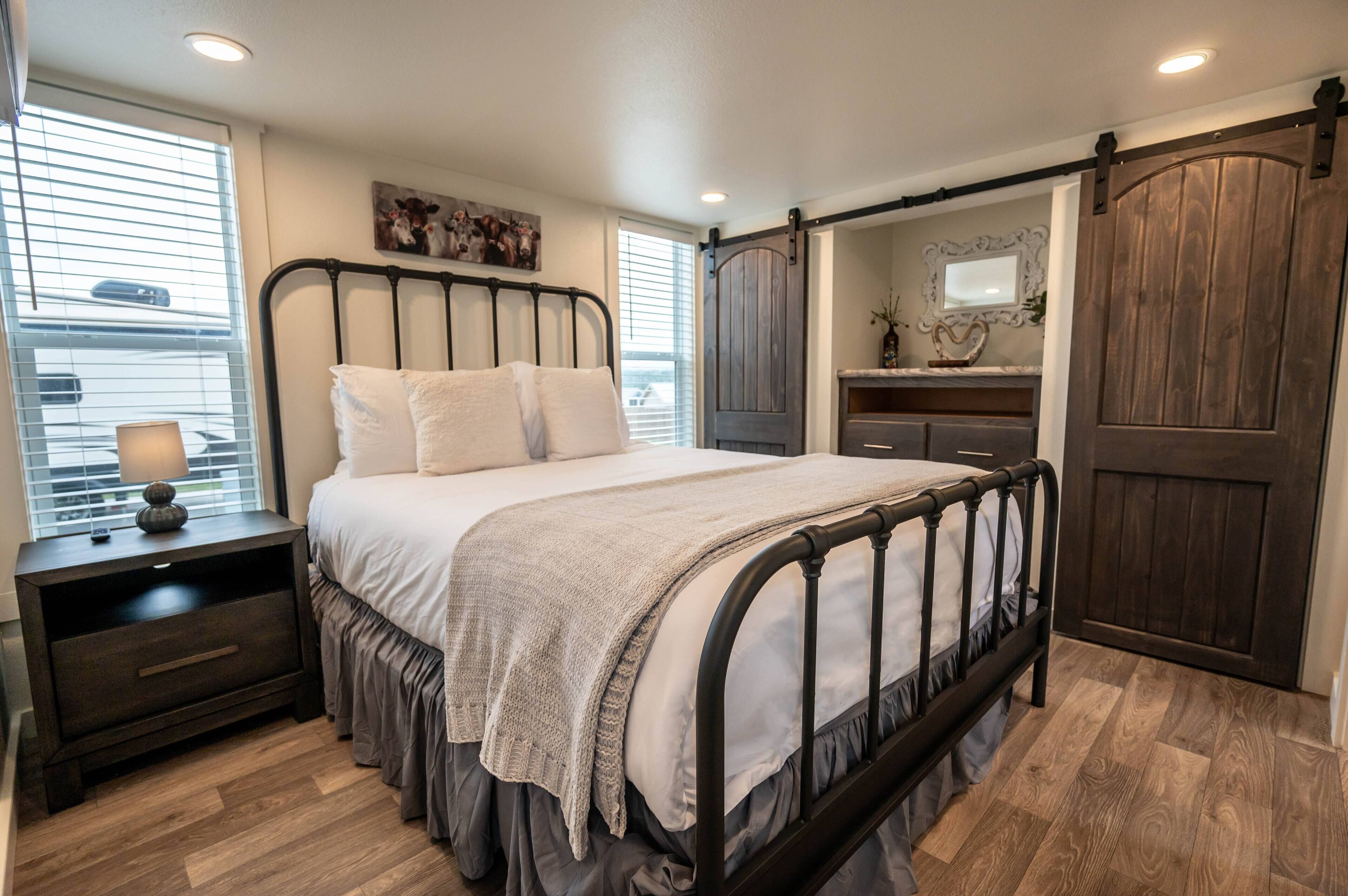 Un dormitorio con cama, mesitas de noche, cómoda y una puerta corrediza de estilo rústico.