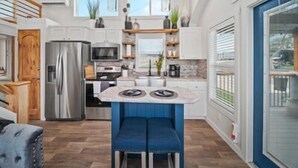 A modern kitchen with a central island, stainless steel appliances, and pendant lighting. - The Charming Chayil Cottage - 046 (Fredericksburg)