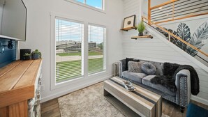 A modern living room with a grey sofa, wooden coffee table, and a staircase with a wooden railing. - The Charming Chayil Cottage - 046 (Fredericksburg)