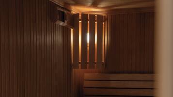 A sauna with wooden benches and benches, with a sloped ceiling and a small window.