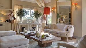 A spacious living room with a white sofa, a wooden coffee table, and a large mirror. - Château de Valmer (La Croix-Valmer)