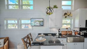 A modern kitchen with white cabinetry, a black countertop, and a dining area with a bench and chairs.
