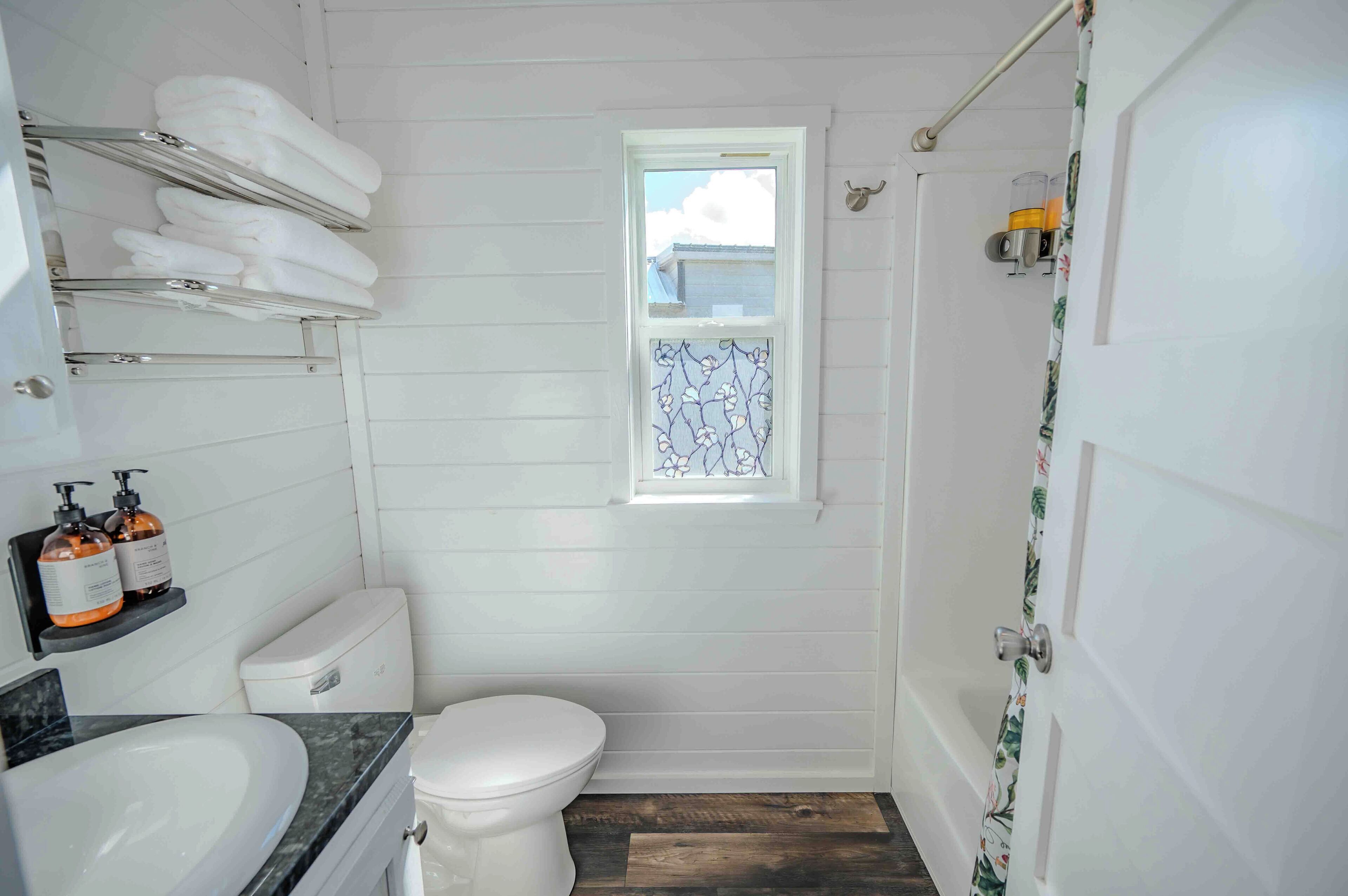 A bathroom with a toilet, sink, and a window with a decorative screen.
