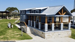 A two-story house with a covered porch, stone foundation, and a metal roof.