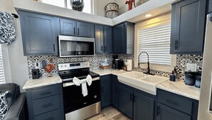 A modern kitchen with dark blue cabinets, a stainless steel oven, a microwave, and a double sink.
