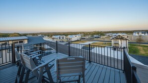 Une terrasse avec des sièges extérieurs et une vue sur un quartier résidentiel, avec des maisons et un ciel dégagé.