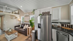 A modern kitchen with white cabinetry, a stainless steel refrigerator, and a built-in dishwasher. - The Haven - 95 (Fredericksburg)