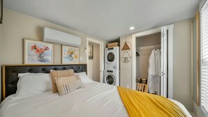 A bedroom with a bed, a washing machine, and a closet. - The Haven - 95 (Fredericksburg)