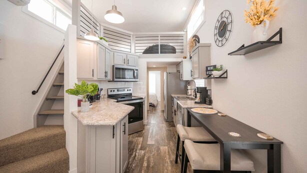 A modern kitchen with a central island, built-in appliances, and a dining area with bar stools. - Cottage on the Hill - 114 (Fredericksburg)