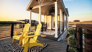 A covered outdoor seating area with yellow chairs and a geometric patterned rug. - Cottage on the Hill - 114 (Fredericksburg)