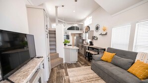 A modern kitchen with a TV, white cabinets, and a central island. - Cottage on the Hill - 114 (Fredericksburg)