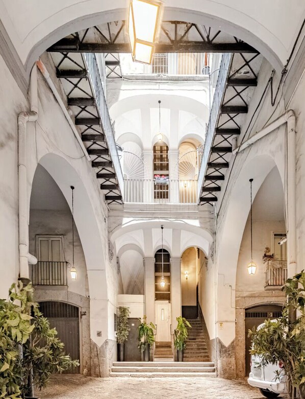 Un intérieur somptueux avec un escalier central, des plafonds en arc de cercle et un lustre.