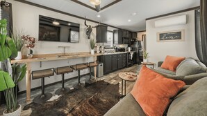 Una cocina moderna con una isla central, taburetes de bar y un ventilador de techo.
