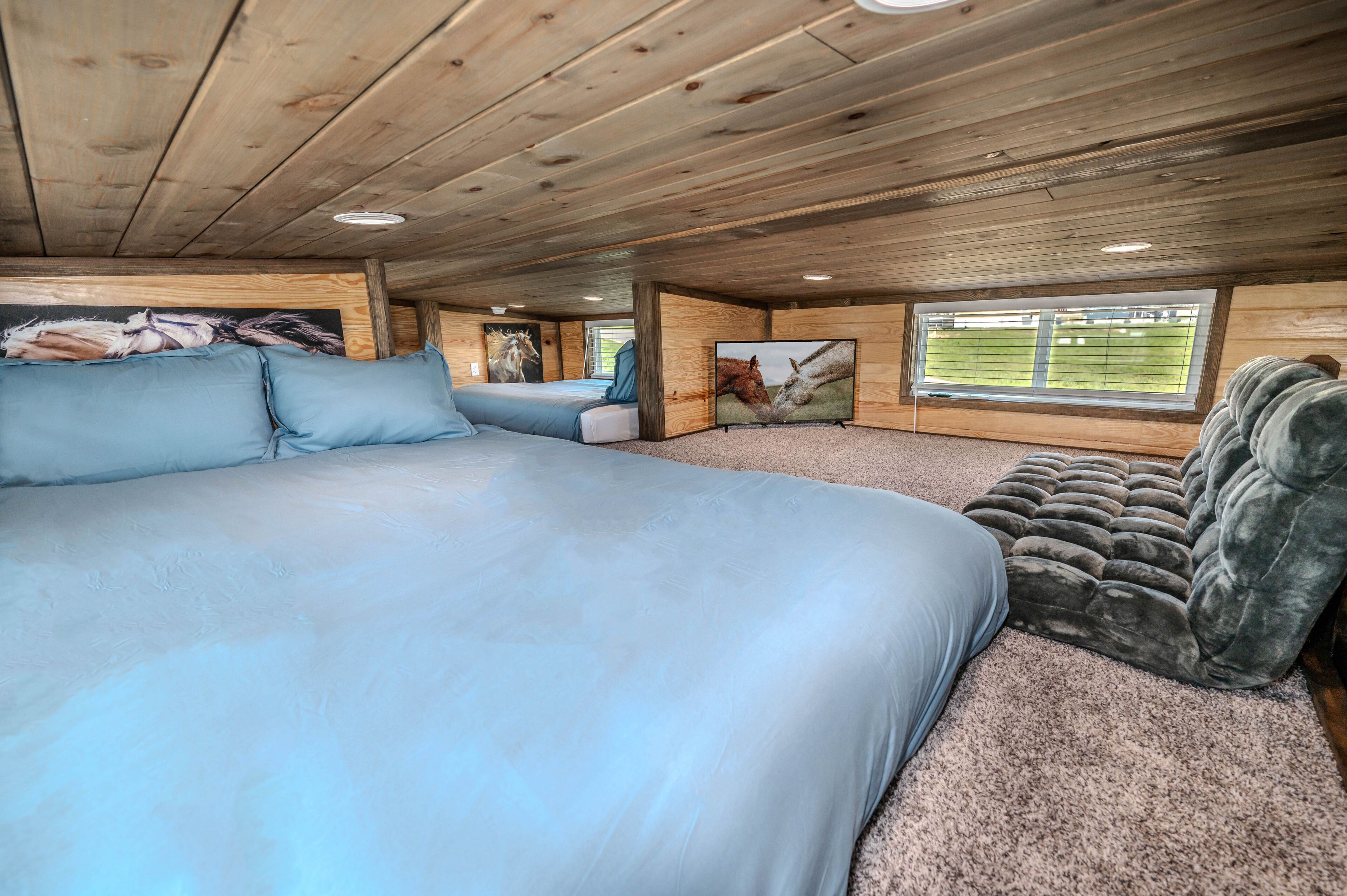A bedroom with a large bed, a sofa, and a window with a view of a field.