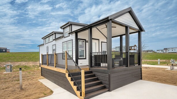 A modern two-story house with a covered porch and a staircase leading to the entrance.