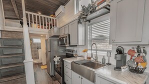 A modern kitchen with a central island, stainless steel appliances, and a built-in microwave. - The Little Haus - 153 (Fredericksburg)