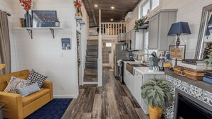 A modern kitchen with white cabinets, a central island, and a built-in stove. - The Little Haus - 153 (Fredericksburg)