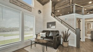A spacious living area with a leather sofa, a coffee table, and a staircase leading to an upper level.