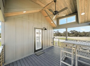 A covered porch with a wooden ceiling, a ceiling fan, and a door leading to an outdoor area.