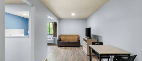 A modern living room with a sofa, TV, and dining area.