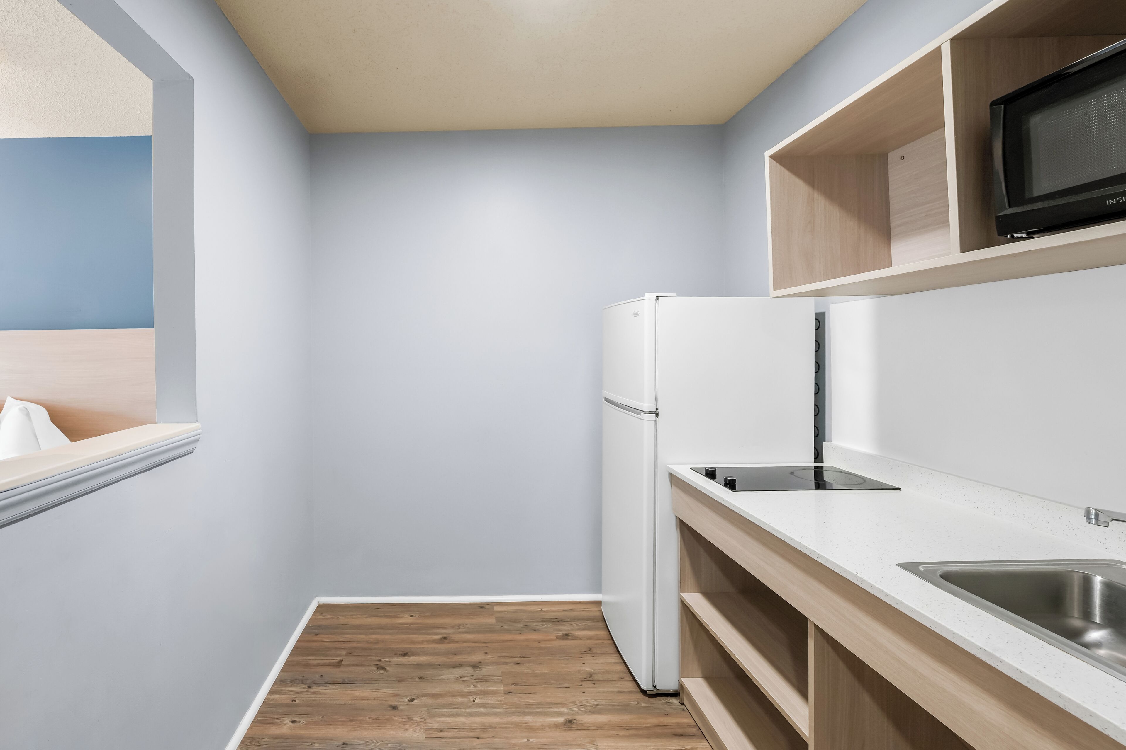 A compact kitchen with a built-in refrigerator, a microwave, and a sink.