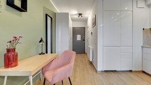 Moderni keittiö, jossa on valkoiset kaapit, puinen työtaso ja vaaleanpunainen tuoli.