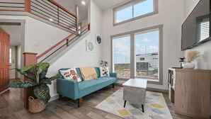 A spacious living room with a staircase, a large window, and a view of the outside.
