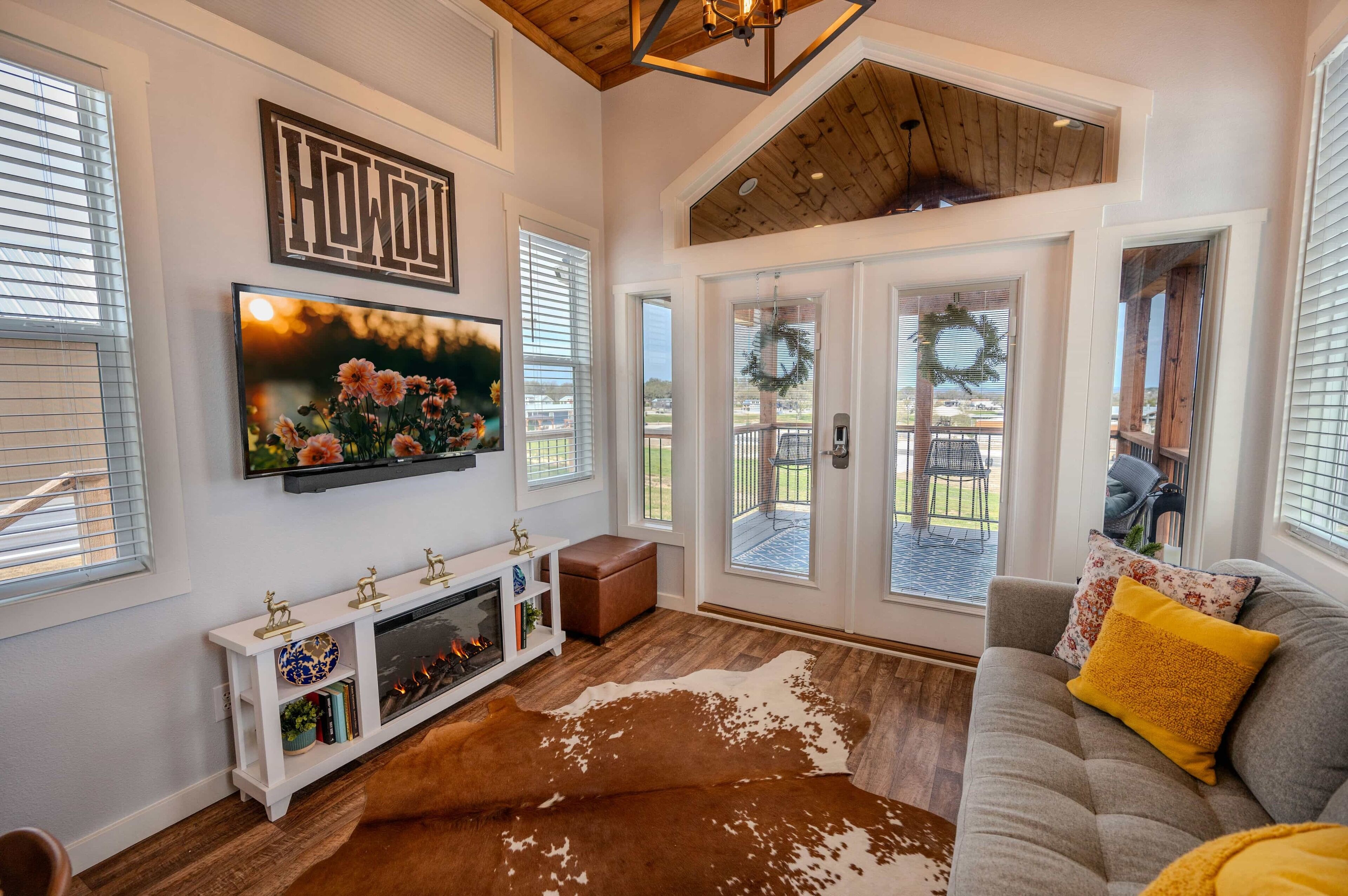 A spacious living room with a fireplace, a large TV mounted above it, and a cowhide rug.
