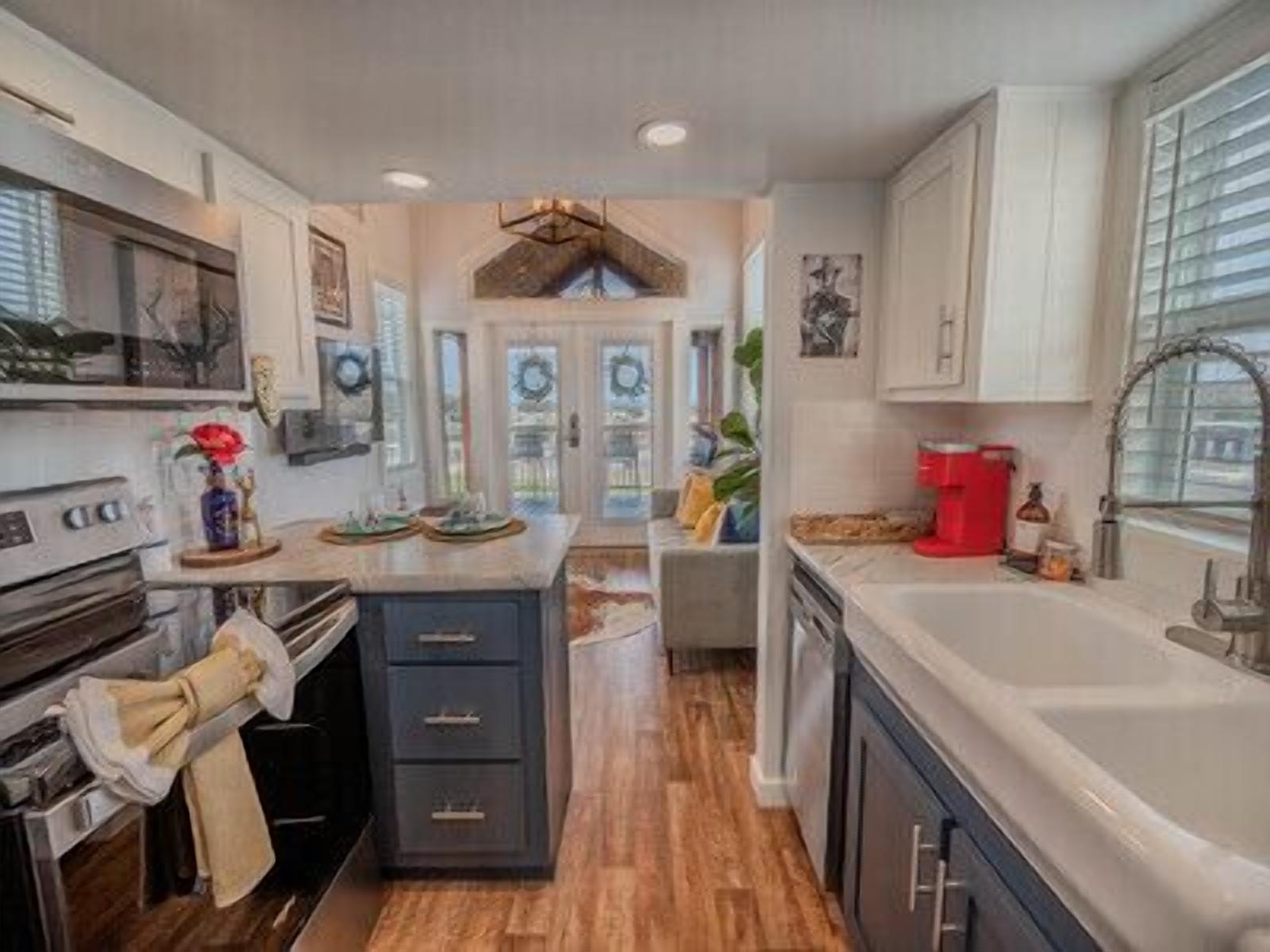 A modern kitchen with dark cabinetry, a central island, and a large window.