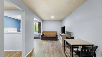 A modern living room with a sofa, TV, and dining area.