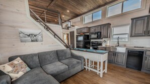 Eine moderne Küche mit einer zentralen Kochinsel, Holzboden und einem grauen Ecksofa.