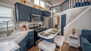 A modern kitchen with dark blue cabinets, a stainless steel microwave, and a wooden island with stools.