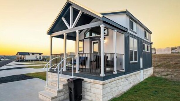 A modern two-story house with a covered porch and a stone foundation.