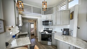 A modern kitchen with white cabinets, stainless steel appliances, and a granite countertop. - Rinconcito Magico - 200 (Fredericksburg)