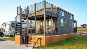 Una autocaravana moderna con una terraza cubierta y una pequeña cocina al aire libre.