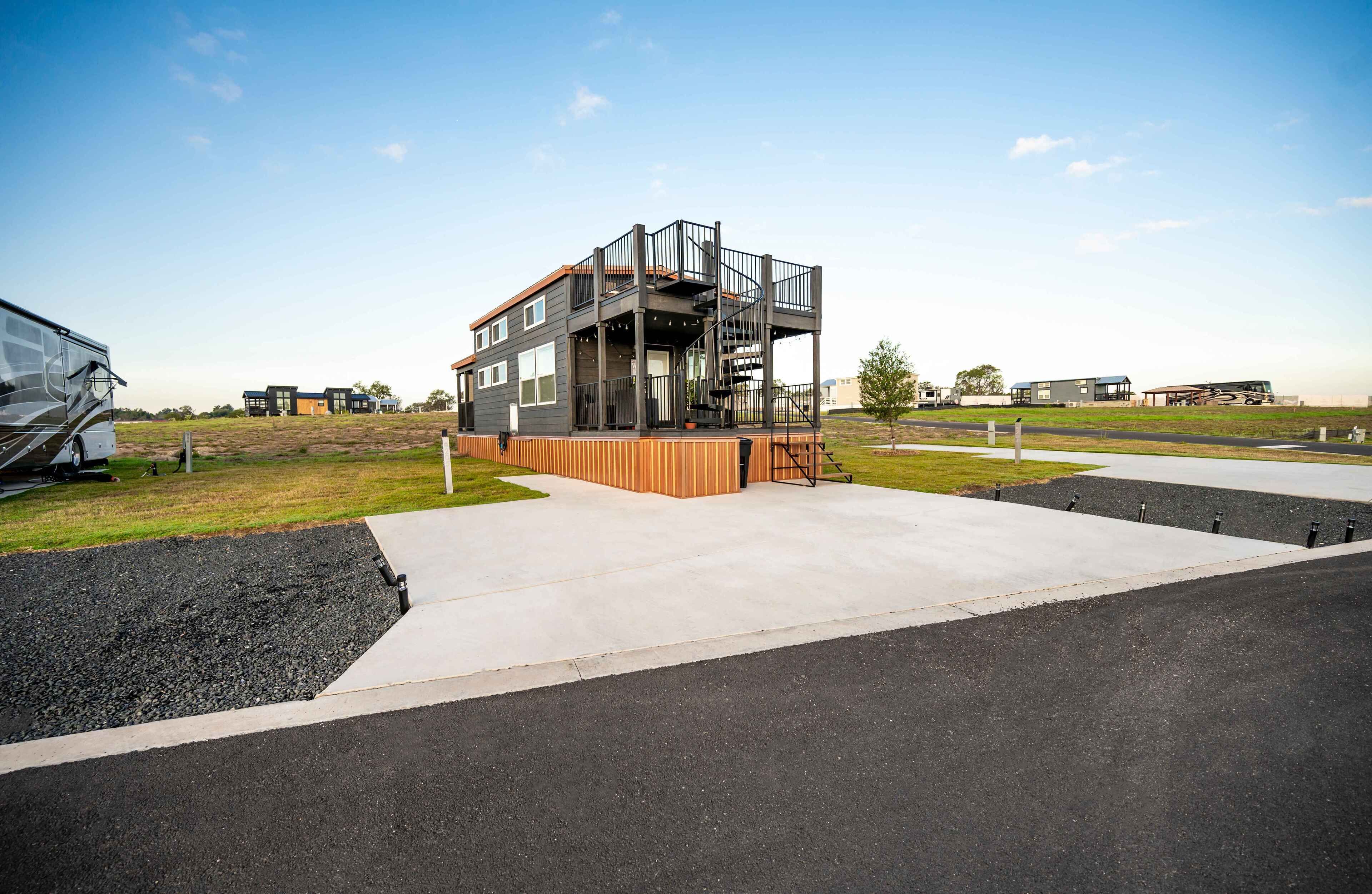 A modern building with a deck, a staircase, and a parking area.