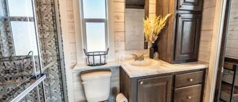 Un baño con inodoro, lavamanos y armarios de madera.