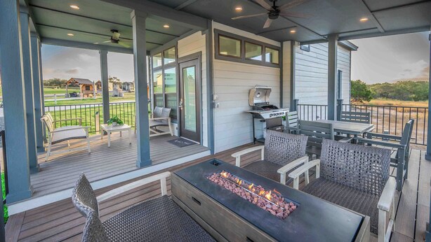 A covered outdoor patio with a fire feature, seating, and a grill area.