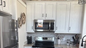 A modern kitchen with white cabinetry, stainless steel appliances, and a herringbone wood floor.