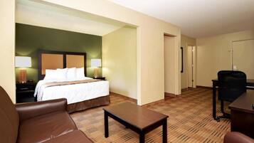 A hotel room with a bed, a desk, a chair, and a small table.