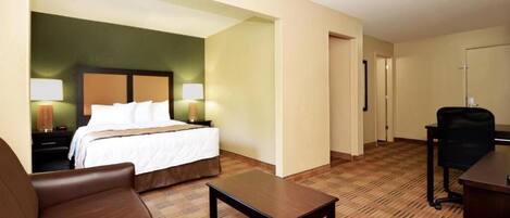 Une chambre d’hôtel avec un lit, un bureau, une chaise et une petite table.