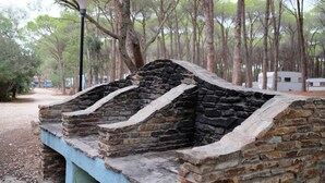 A stone structure with a ramp, surrounded by trees. - Happy Camp in Selema Camping (Siniscola)