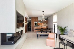 A modern kitchen with a dining area, a sofa, and a TV.